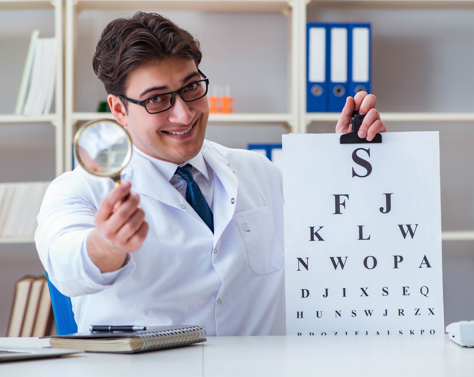 Optometrist, male optometrist, male optometrist in an optical clinic, optometrist holding a lens in an optical clinic