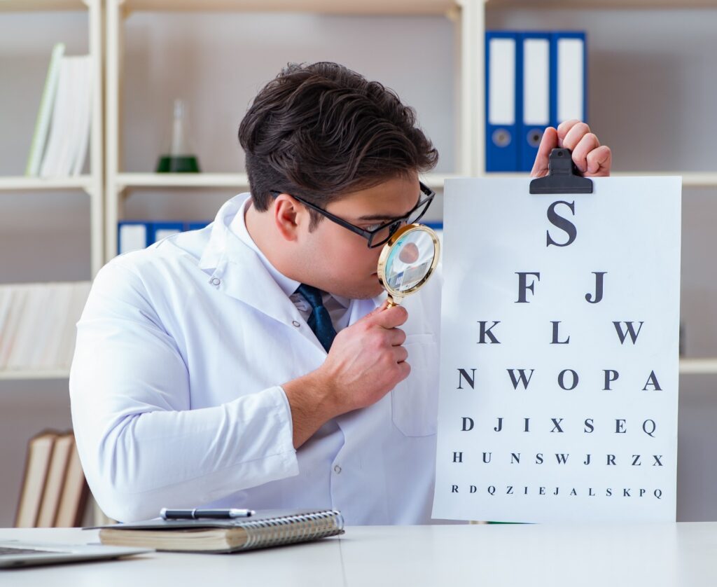Optometrist, male optometrist, male optometrist in an optical clinic, optometrist using a lens to view writings in an optical clinic